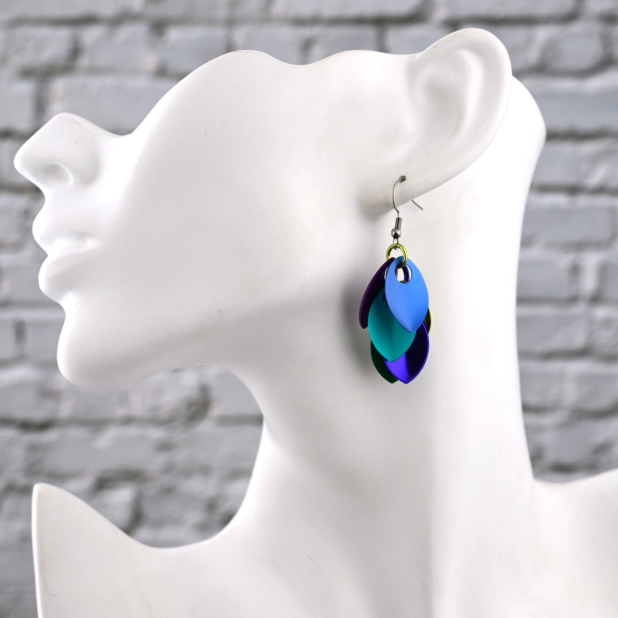 Side view of a white mannequin wearing one Peacock Cascading Leaves Earring to show how the short drop sits against the neck