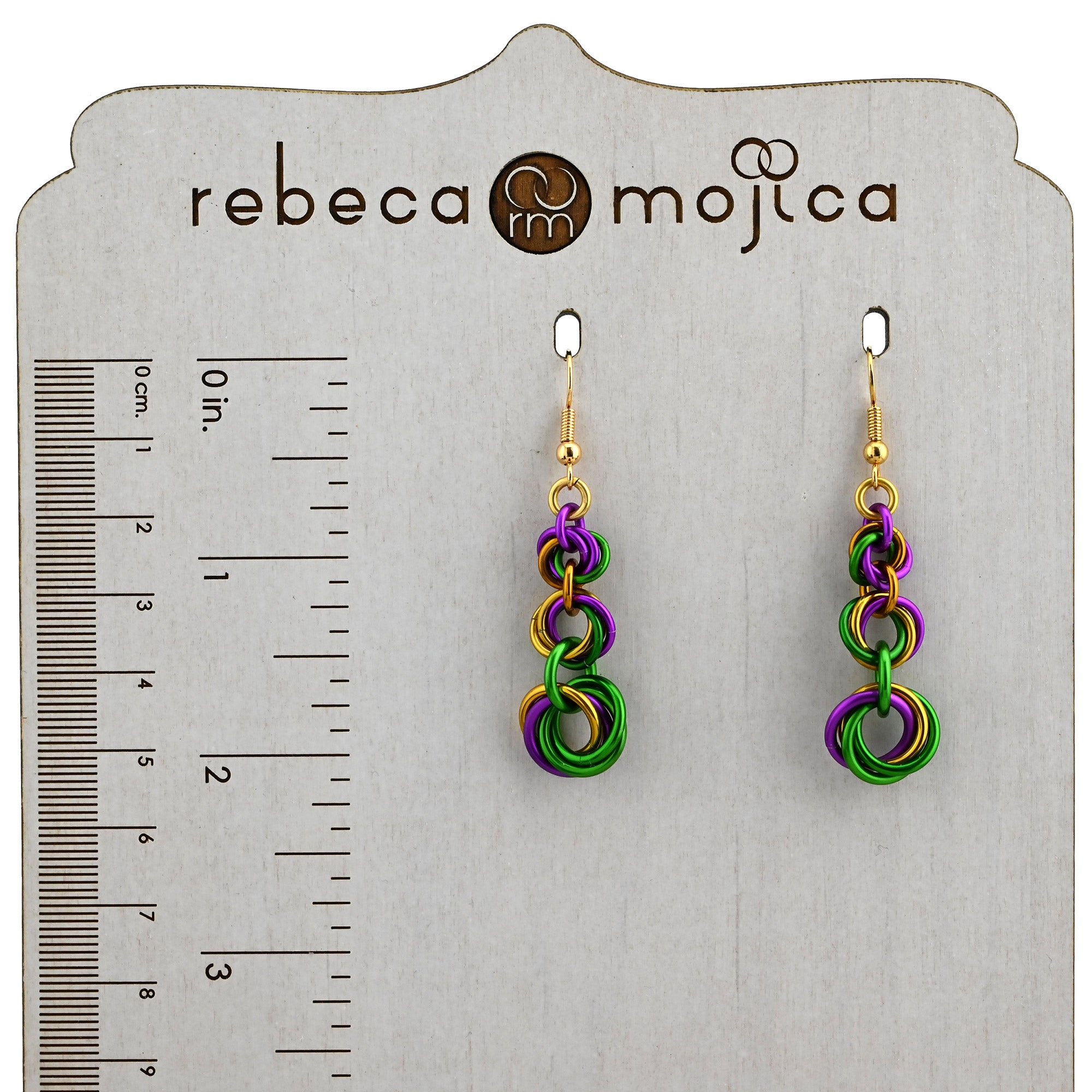 Graduated Mardi Gras knot earrings on a branded display card next to a ruler showing a length of approximately 2 inches.