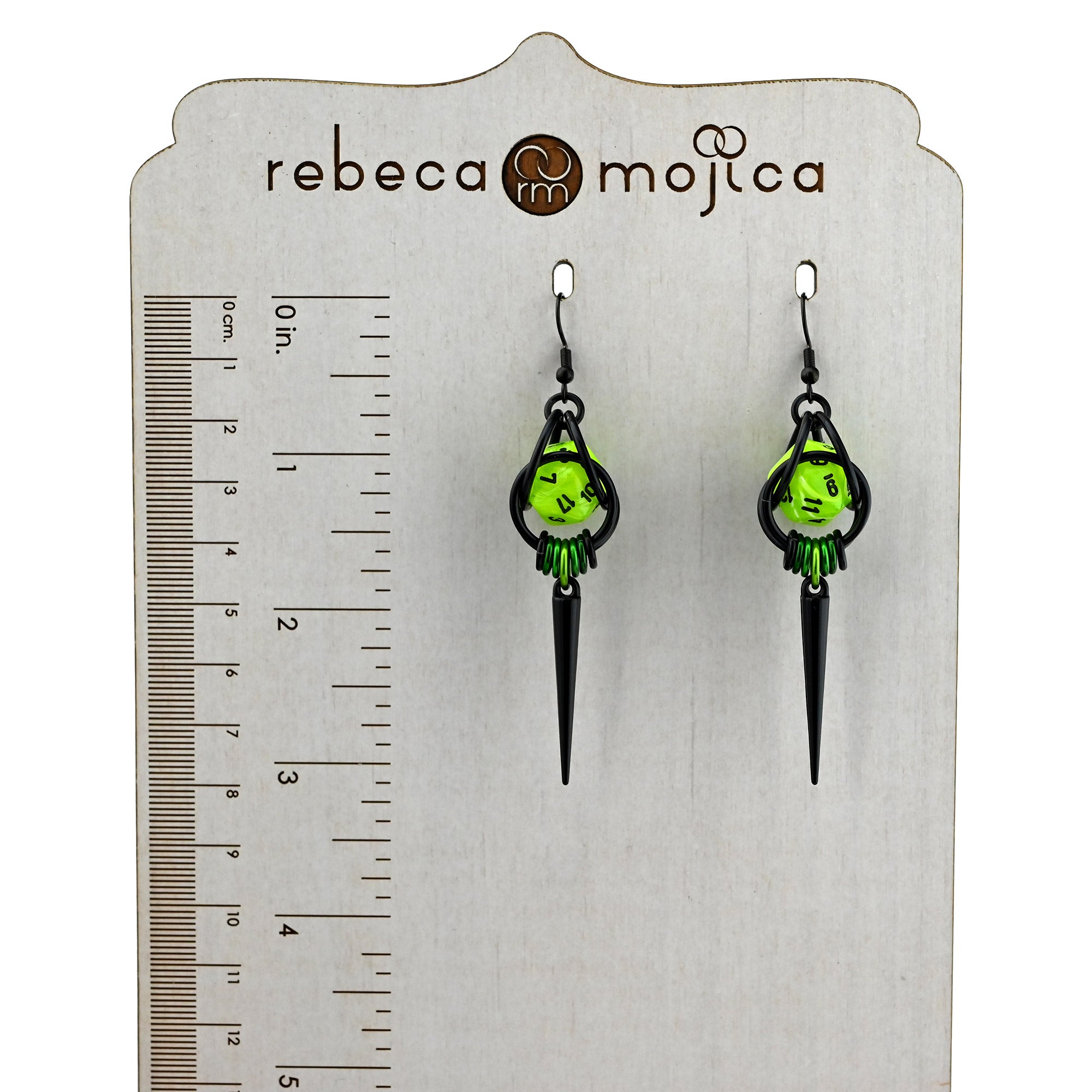 Neon green dice earrings next to a ruler showing a 3.25-inch length from the earwire to the tip of the black spike
