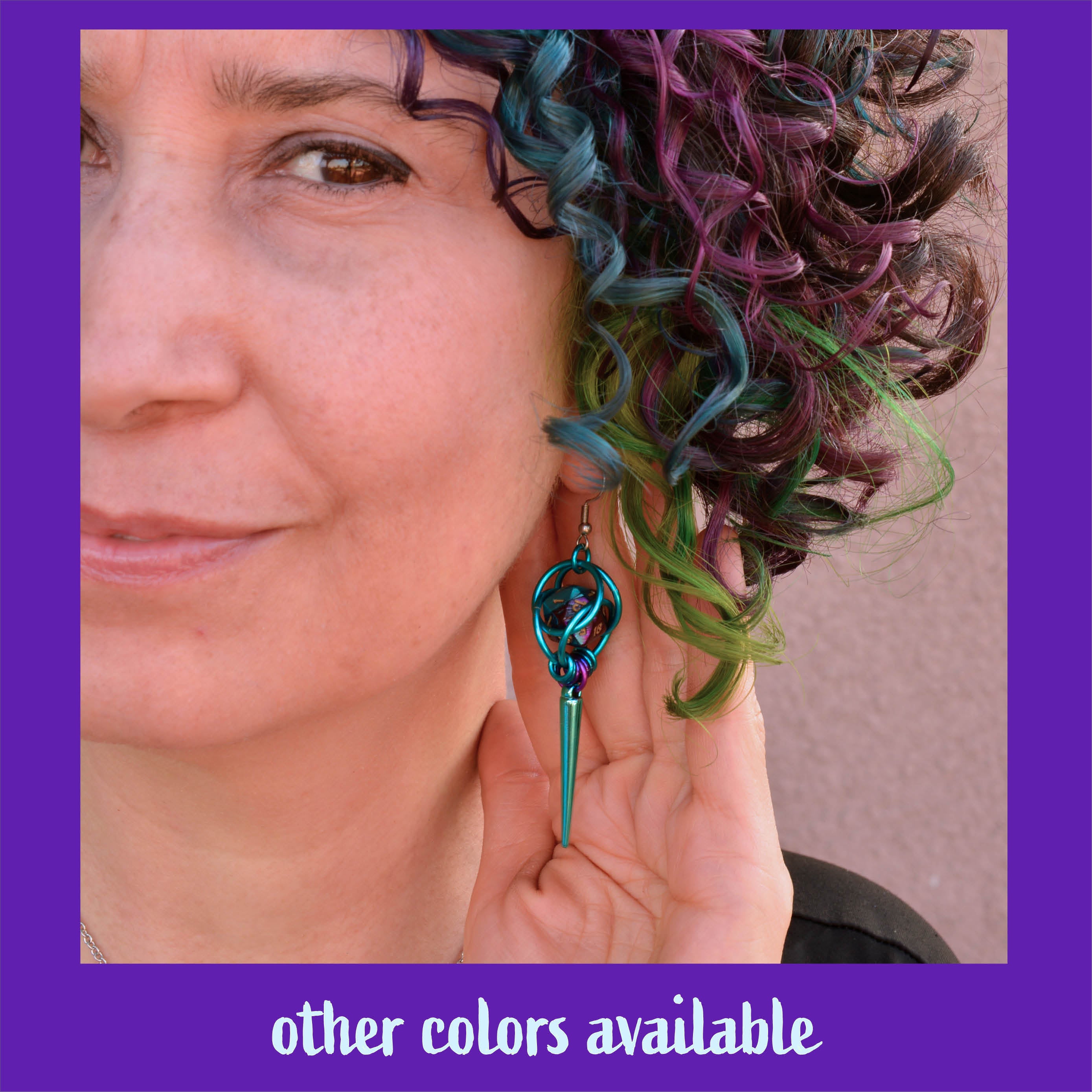 Lifestyle shot of a person with colorful purple and blue hair wearing a teal version of the D20 spike earrings. Text at the bottom reads "other colors available."