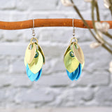 Close-up of seashell ombre chainmaille earrings hanging on a tree branch, highlighting the champagne, seafoam, and light blue colors.