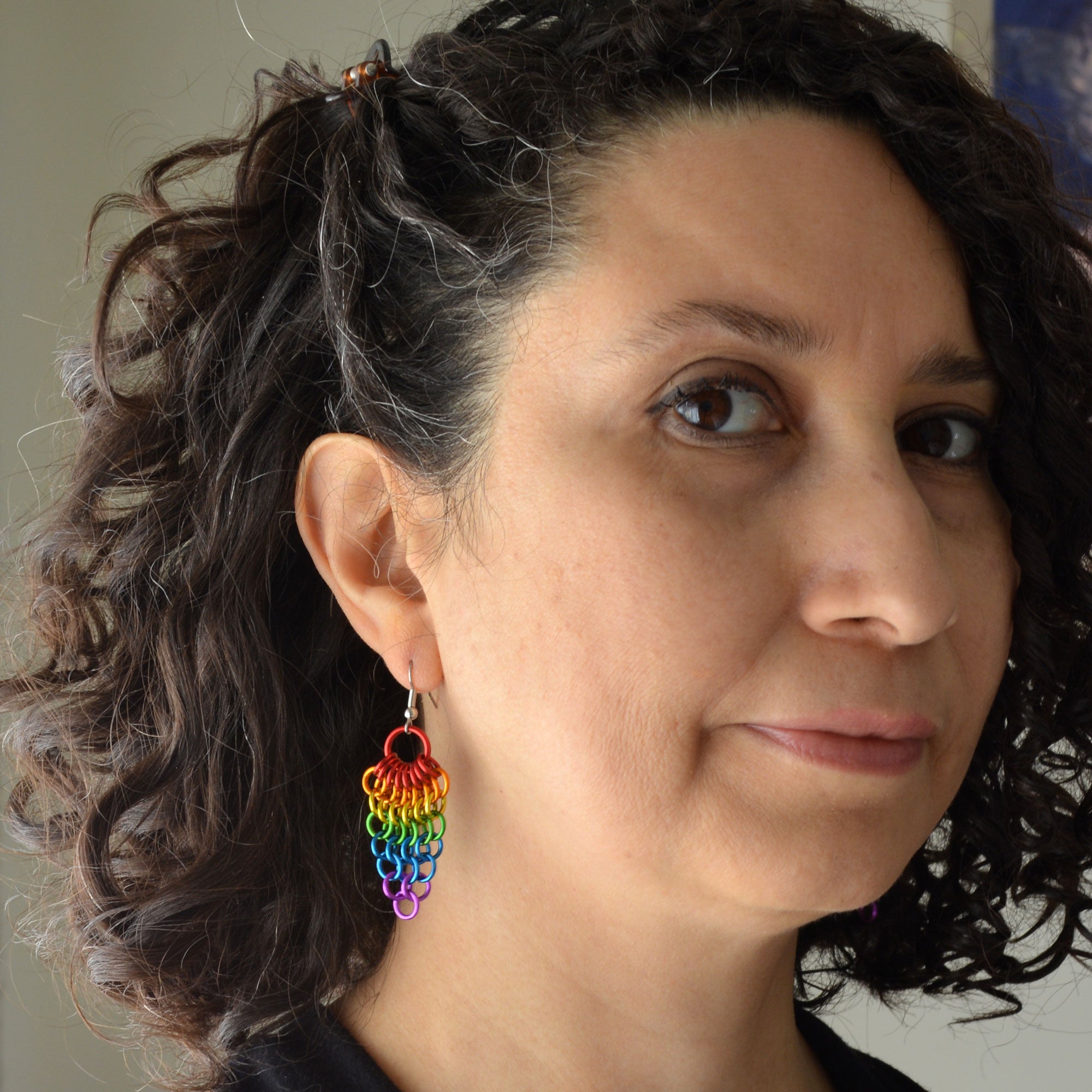 Artisan Rebeca Mojica wearing a pair of rainbow Mesh Cluster earrings.