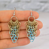 Closeup of chainmaille cluster mesh earrings resting in the fingertips of chainmaille artisan Rebeca Mojica. This photo provides a sense of the scale and lightness of the jewelry.