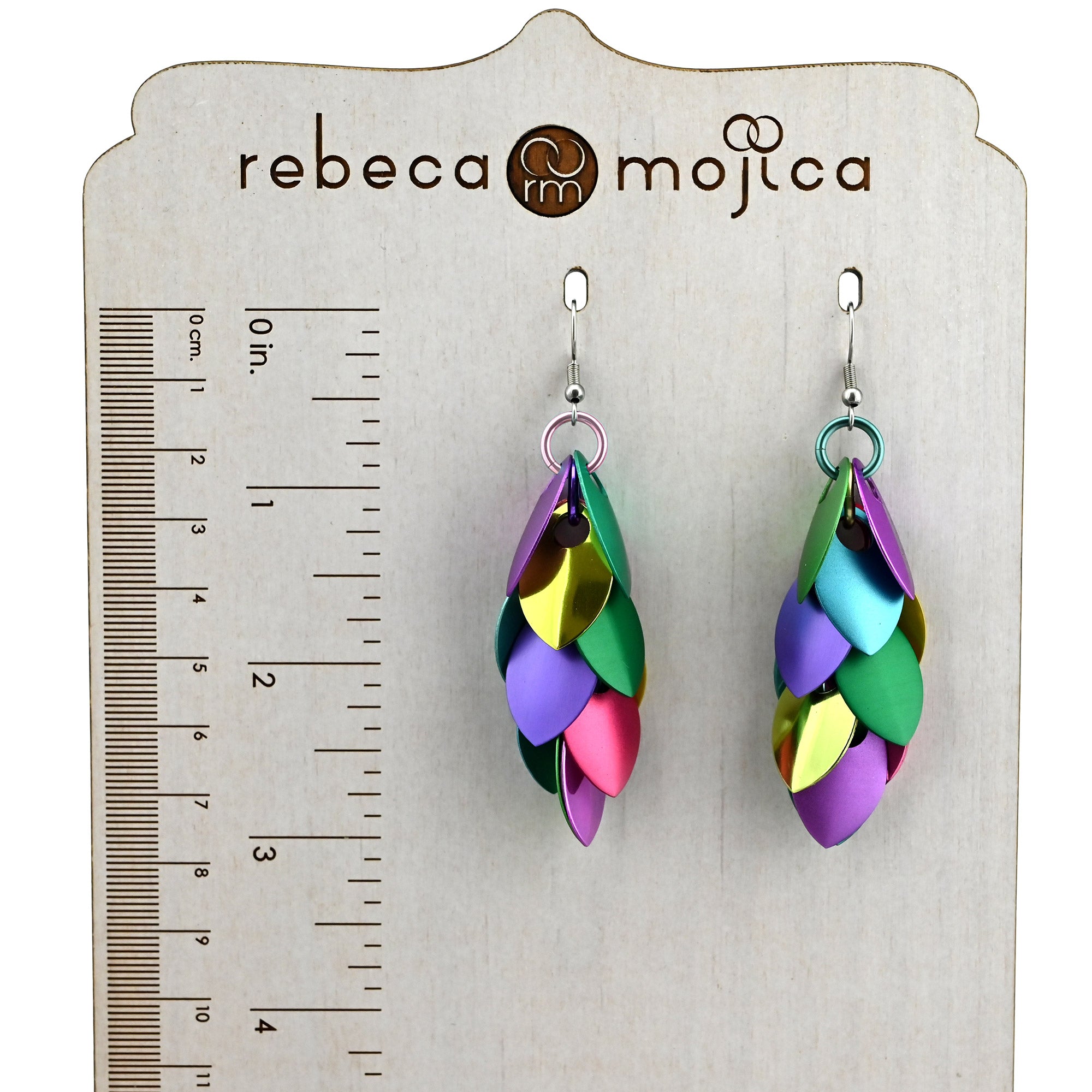 Long pastel colored scalemaille earrings shown on a branded display stand with a ruler, measuring approximately 3 inches from the top of the earwire.