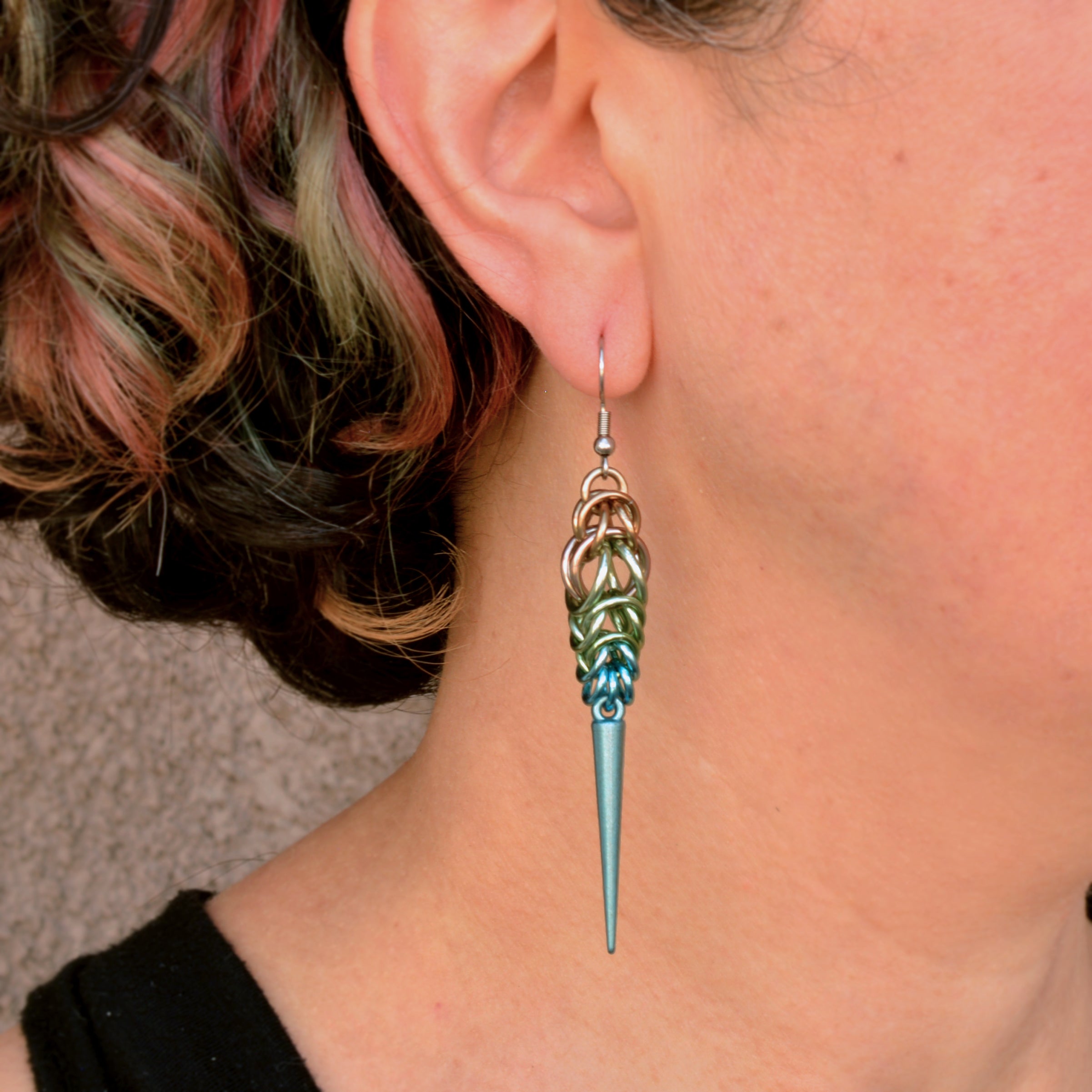 Chainmaille artisan Rebeca Mojica wearing one of her handmade Seashell Ombre Spike Earrings to show the scale and how it looks when worn.