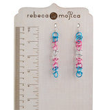 Trans Pride Earrings Length: Long, lightweight chainmaille earrings (matte trans pride flag colors) on a branded Rebeca Mojica wooden stand. Approximately 3.5 inches long.