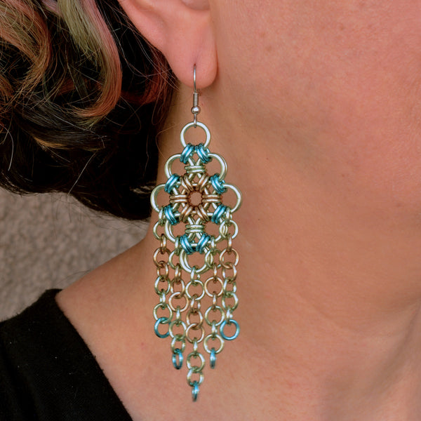 Statement chainmaille earring worn by artisan Rebeca Mojica, showcasing its length and how it hangs from the ear.