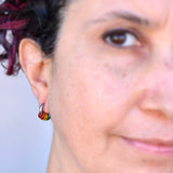 Rainbow pride huggie earring (8 mm stainless steel) being worn on artisan Rebeca Mojica.