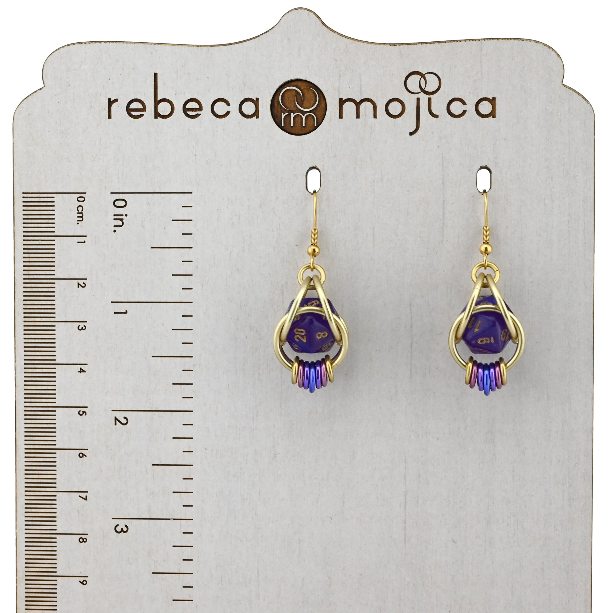  Wisteria Fae dice earrings shown on a branded Rebeca Mojica Jewelry display with to a ruler, measuring approximately 1.75 inches in length.