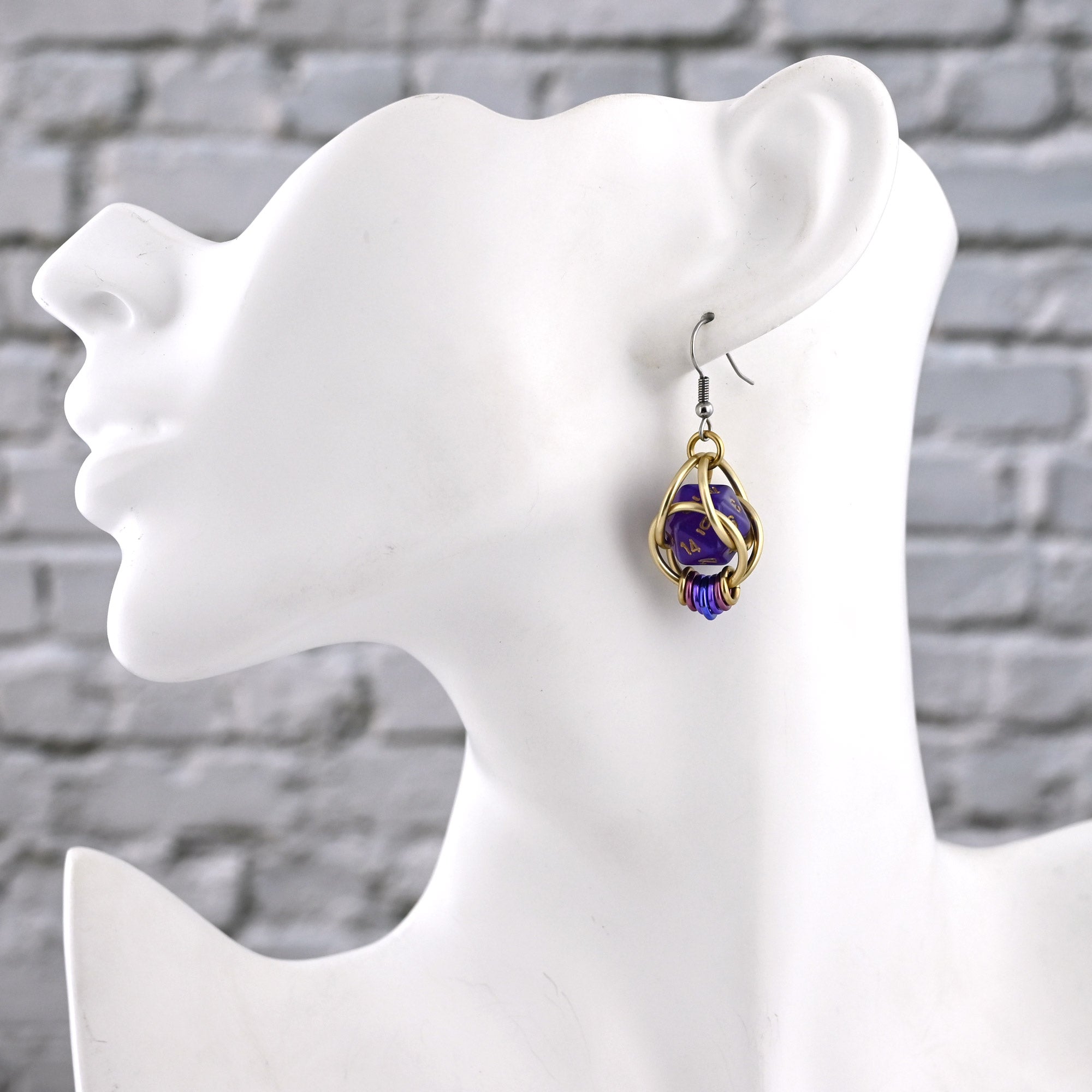 Side view of a mannequin wearing one Wisteria Fae earring with stainless steel earwire, showing how the dice cage hangs just below the jawline.