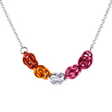 Closeup of chainmaille necklace in lesbian pride colors on a white background