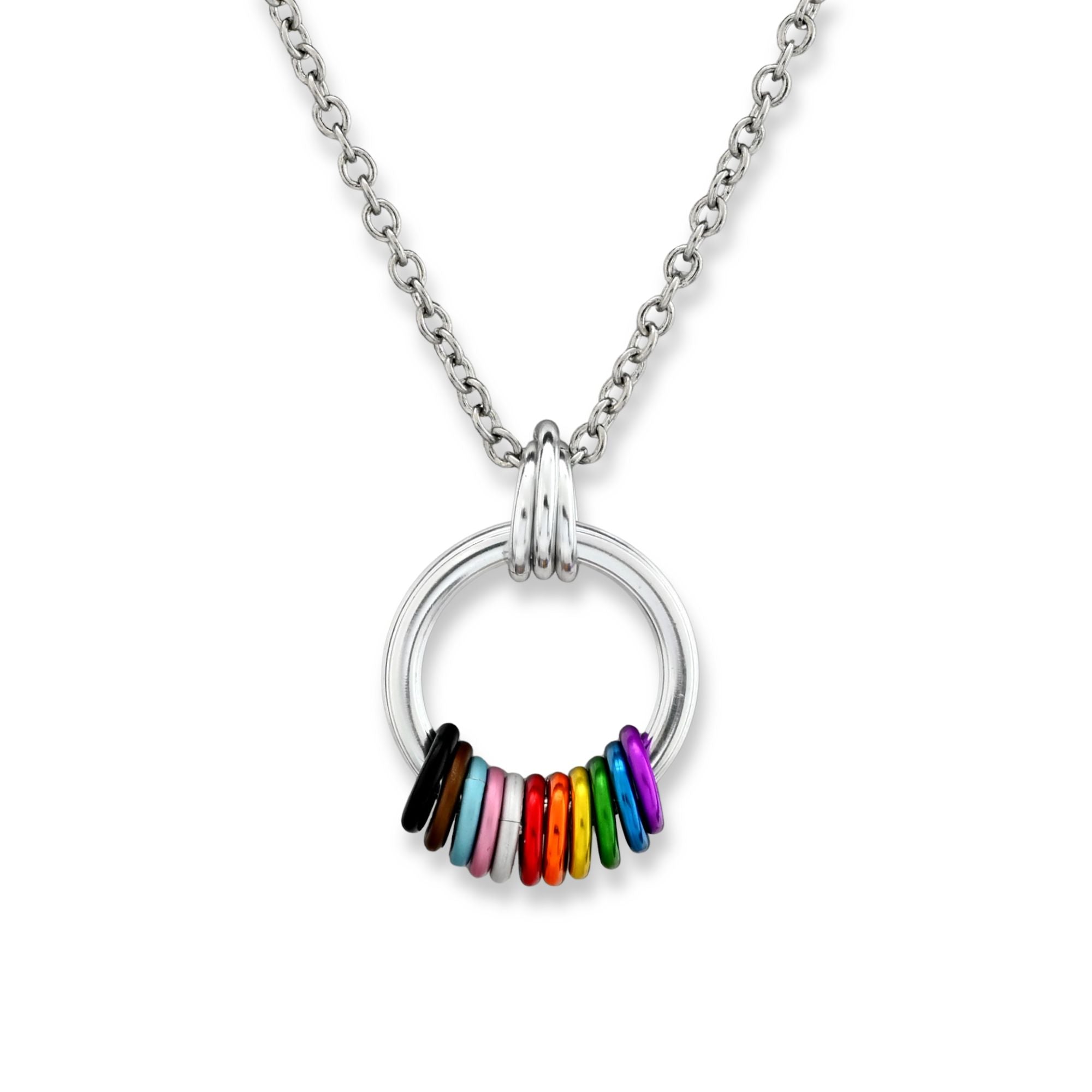A minimalist silver-tone circular pendant on a stainless steel chain against a crisp white background. The bottom of the circle features free-spinning aluminum rings in a vibrant rainbow sequence of red, orange, yellow, green, blue, and purple.