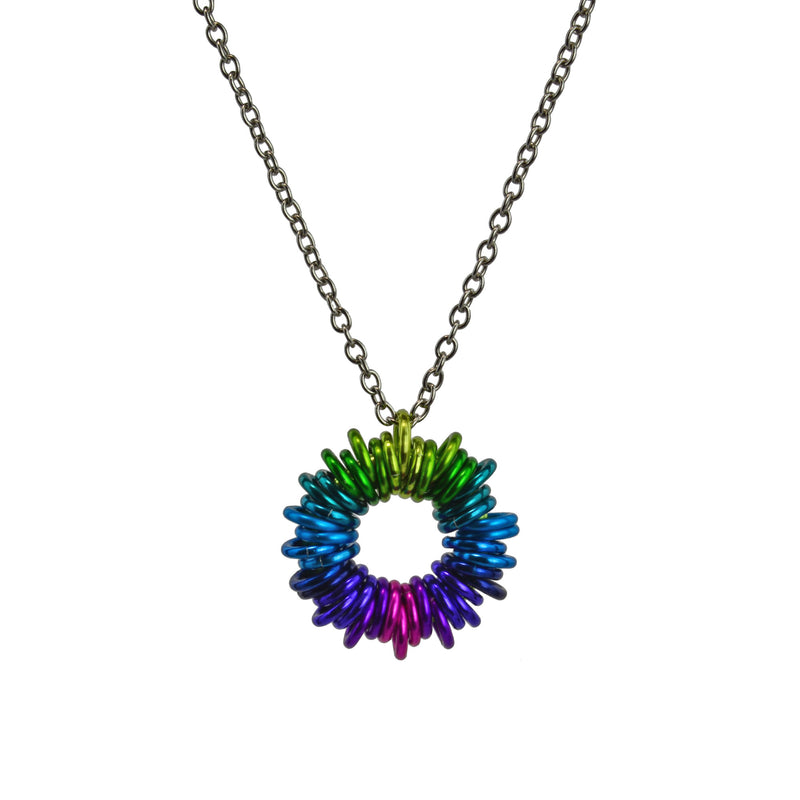 Coiled Pendant in Electric Rainbow by Rebeca Mojica. Approximately 40 small anodized aluminum jump rings are added to a larger jump ring forming a "coil" motif. The colors range from lime to teal to turqouise to blue to purple to violet to pink and back again.