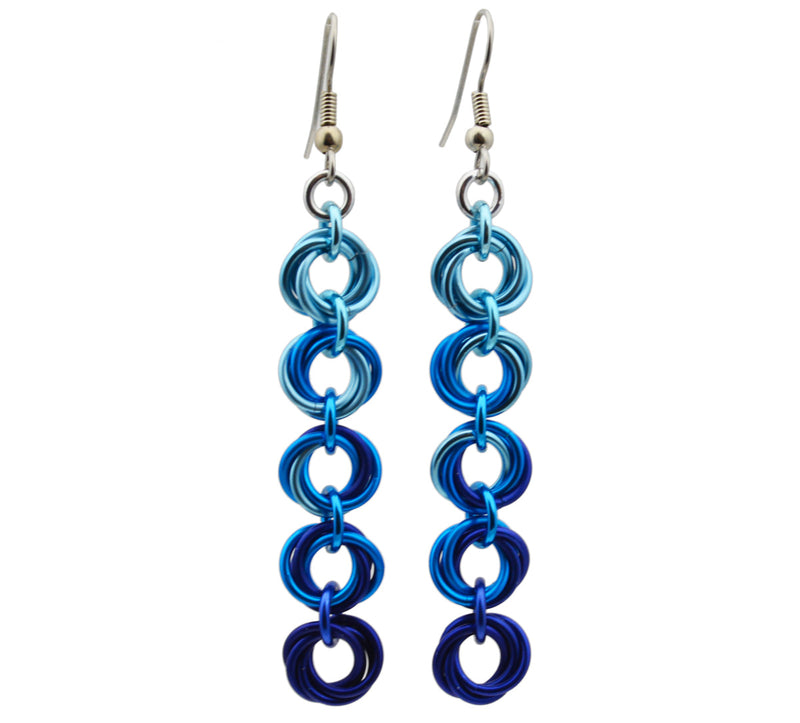 Chainmaille earrings of 5 linked "knots" hanging from the earwire. Top knot is light blue, transitioning as you move down the earring to medium blue and dark blue. chainmaille earrings by Rebeca Mojica