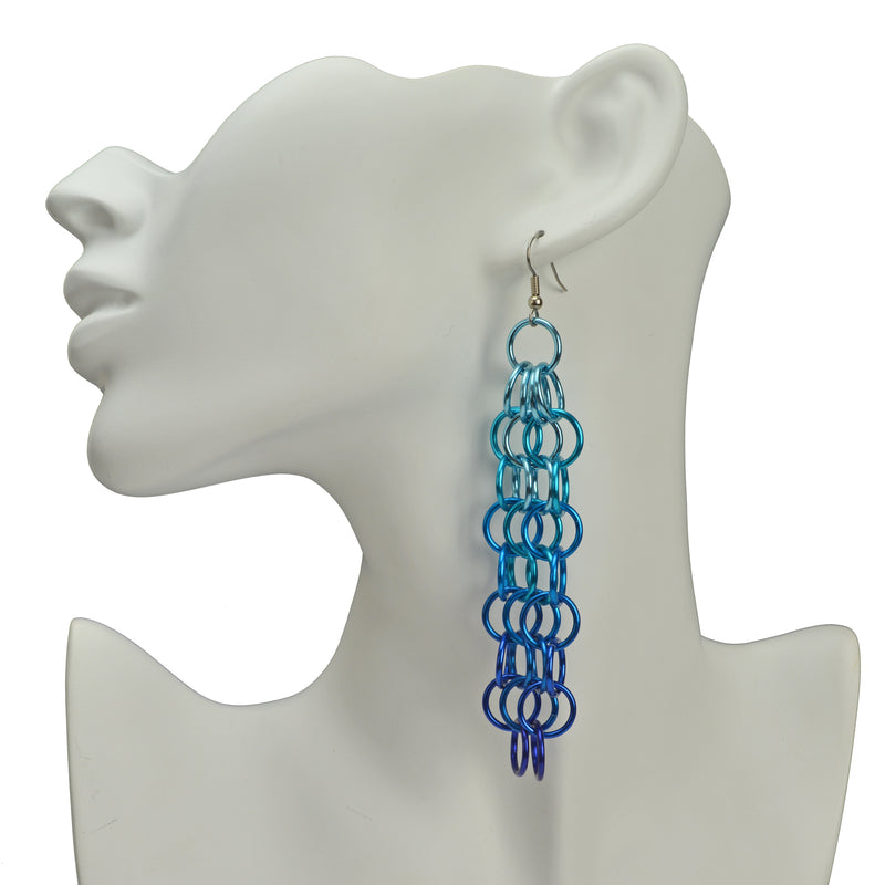 Large link chain mesh long statement earring in light blue, azure and blue ombre. Earring is hung from the ear of a white display head
