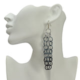 Large link chain mesh long statement earring in silver, grey and black ombre. Earring is hung from the ear of a white display head