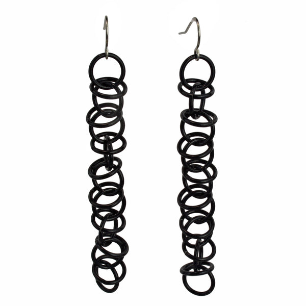 Long earrings made of thin black jump rings. The links are joined in a 1-1-1 chain, with additional loose rings "orbiting" around the main chain.