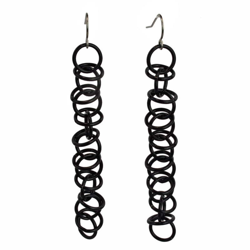 Long earrings made of thin black jump rings. The links are joined in a 1-1-1 chain, with additional loose rings "orbiting" around the main chain.
