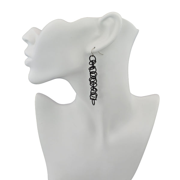 Long black Orbital earrings by Rebeca Mojica Jewelry displayed on white neck form.