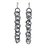Long earrings made of thin grey jump rings. The links are joined in a 1-1-1 chain, with additional loose rings "orbiting" around the main chain.