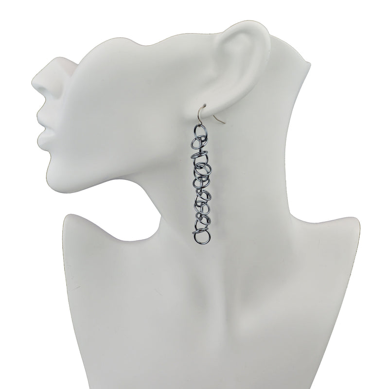Long grey orbital earrings by Rebeca Mojica on white display form.