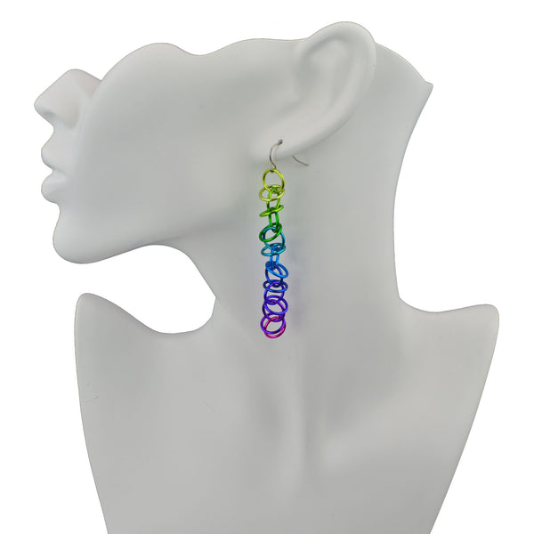 Long electric rainbow Orbital earrings by Rebeca Mojica Jewelry displayed on white neck form.