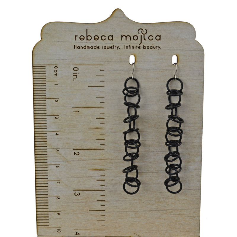 Black Orbital chainmaille earrings on ruler display showing earrings measure 3 inches long.