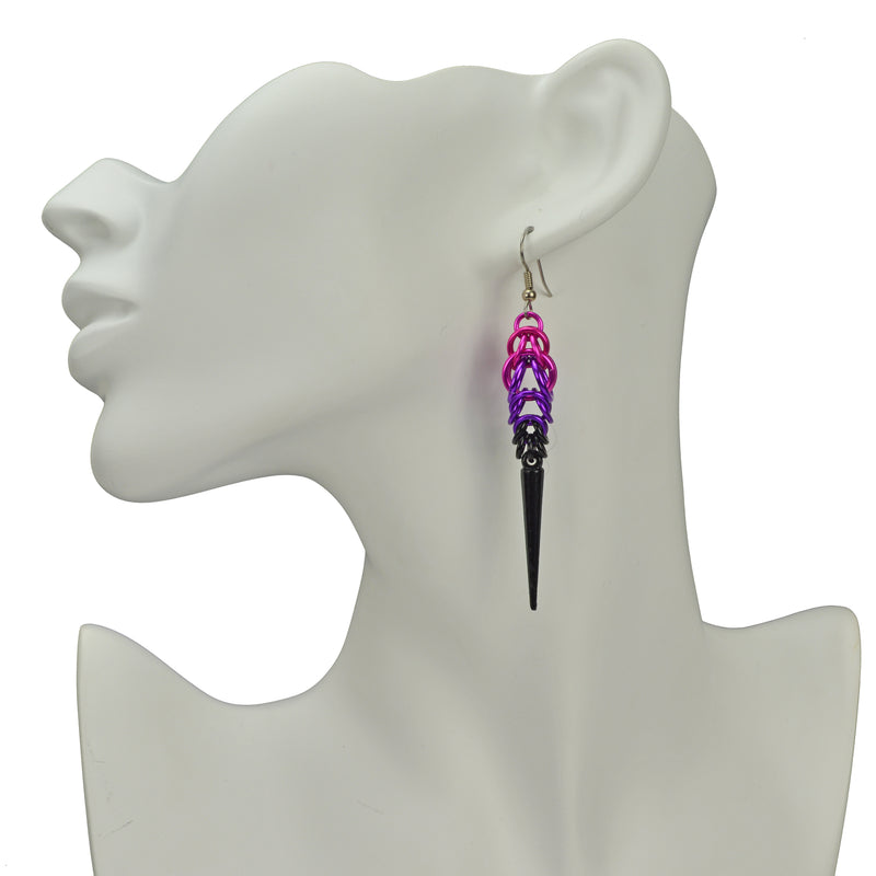 Chainmaille spike earrings on a white display head form. Earrings are pink at the top, transitioning to violet and finishing with small black links and a long black spike. 